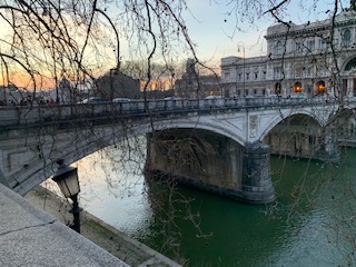 bridge spanning river with tree branches in foreground
